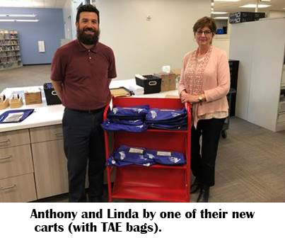 HCPL employees Anthony and Linda, standing by a cart full of TAE bags